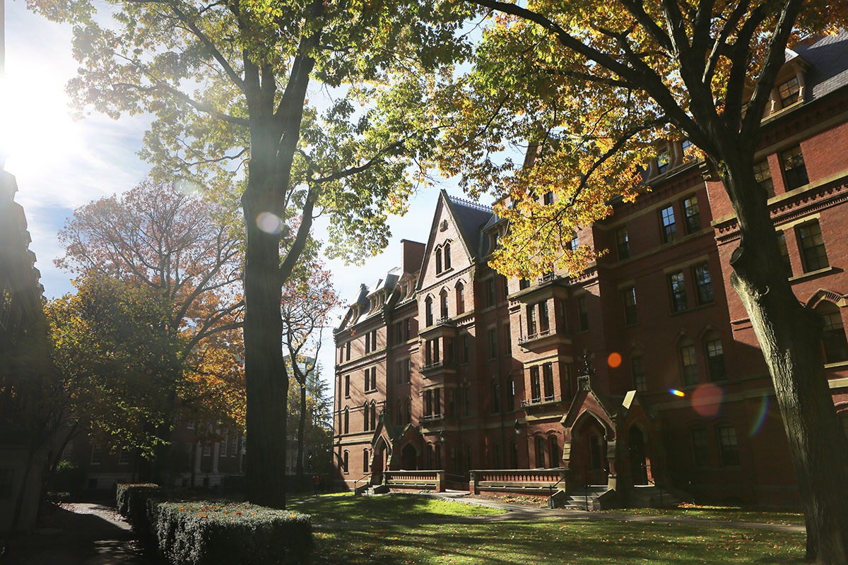 Stately four- to five-story red brick building on a higher education campus surrounded by trees